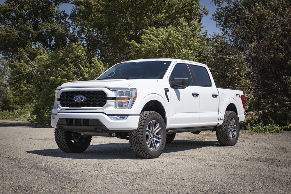 1-02-2022-ford-f150-white-lifted-4x4-trees-gravel