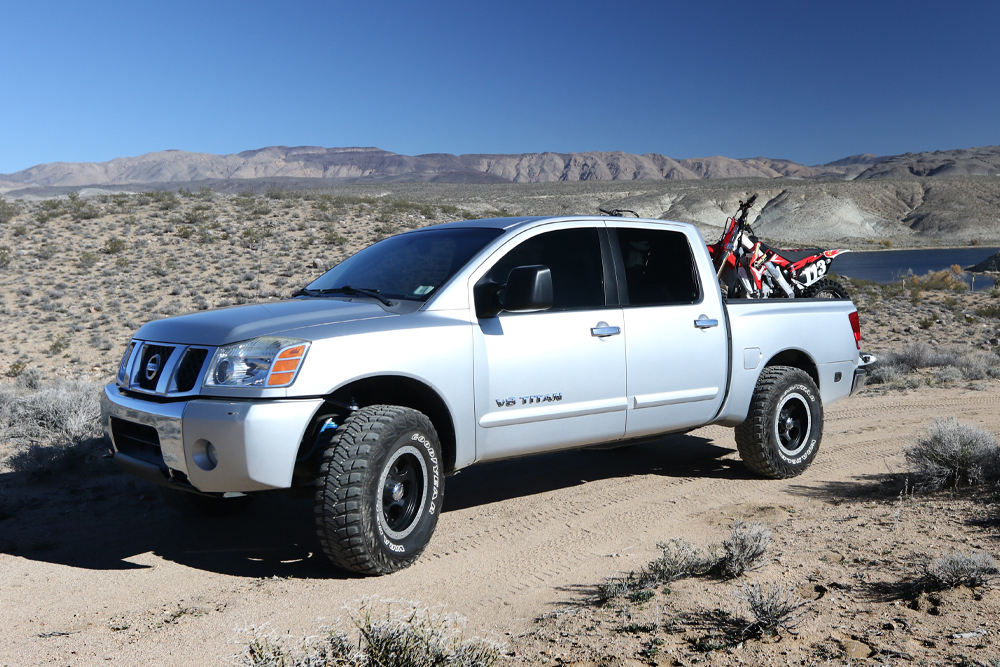 silver-nissan-titan-dirtbike-in-bed-lifted-off-road-suspension-desert-honda